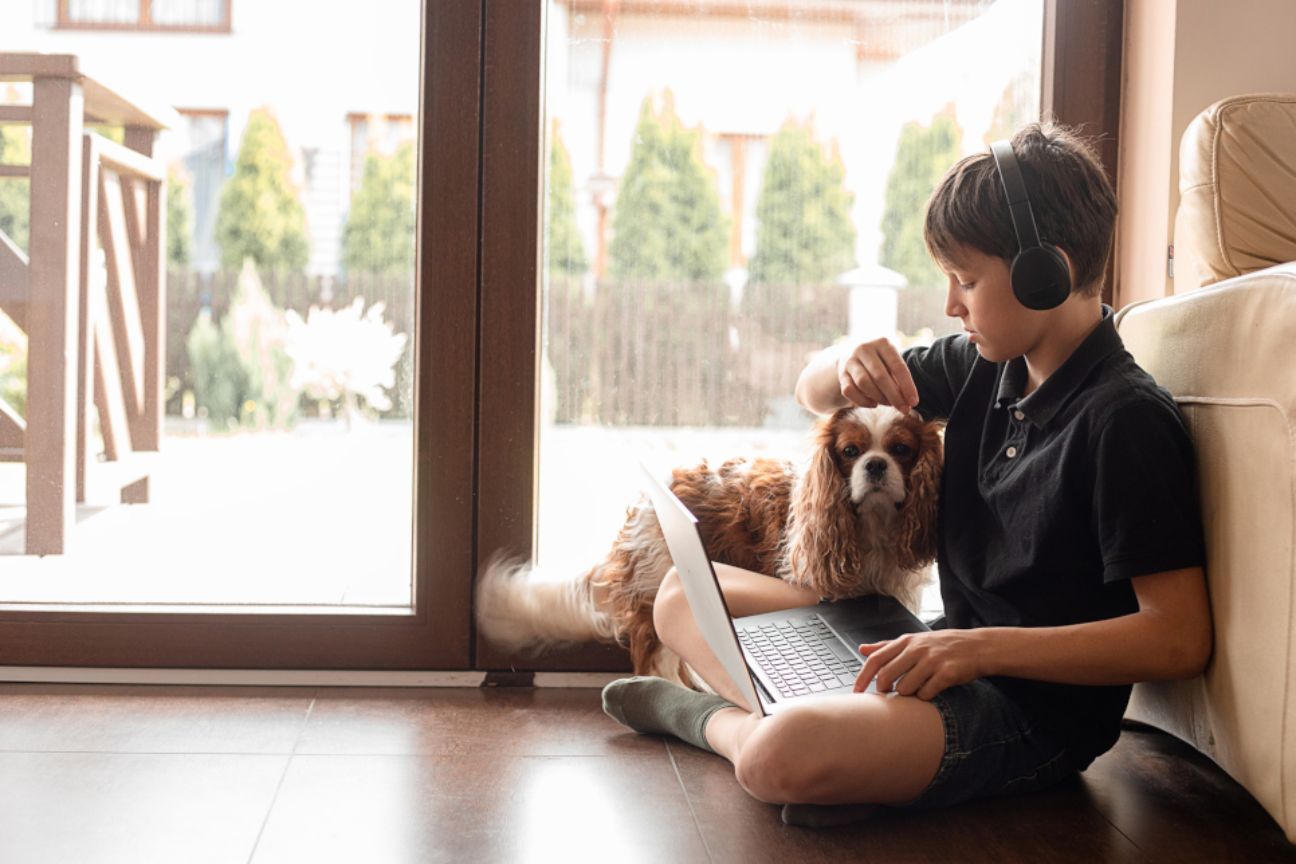 Child at home with pet and computer.
